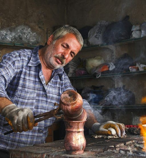 Artisan marocain travaillant une piece de cuivre dans son atelier